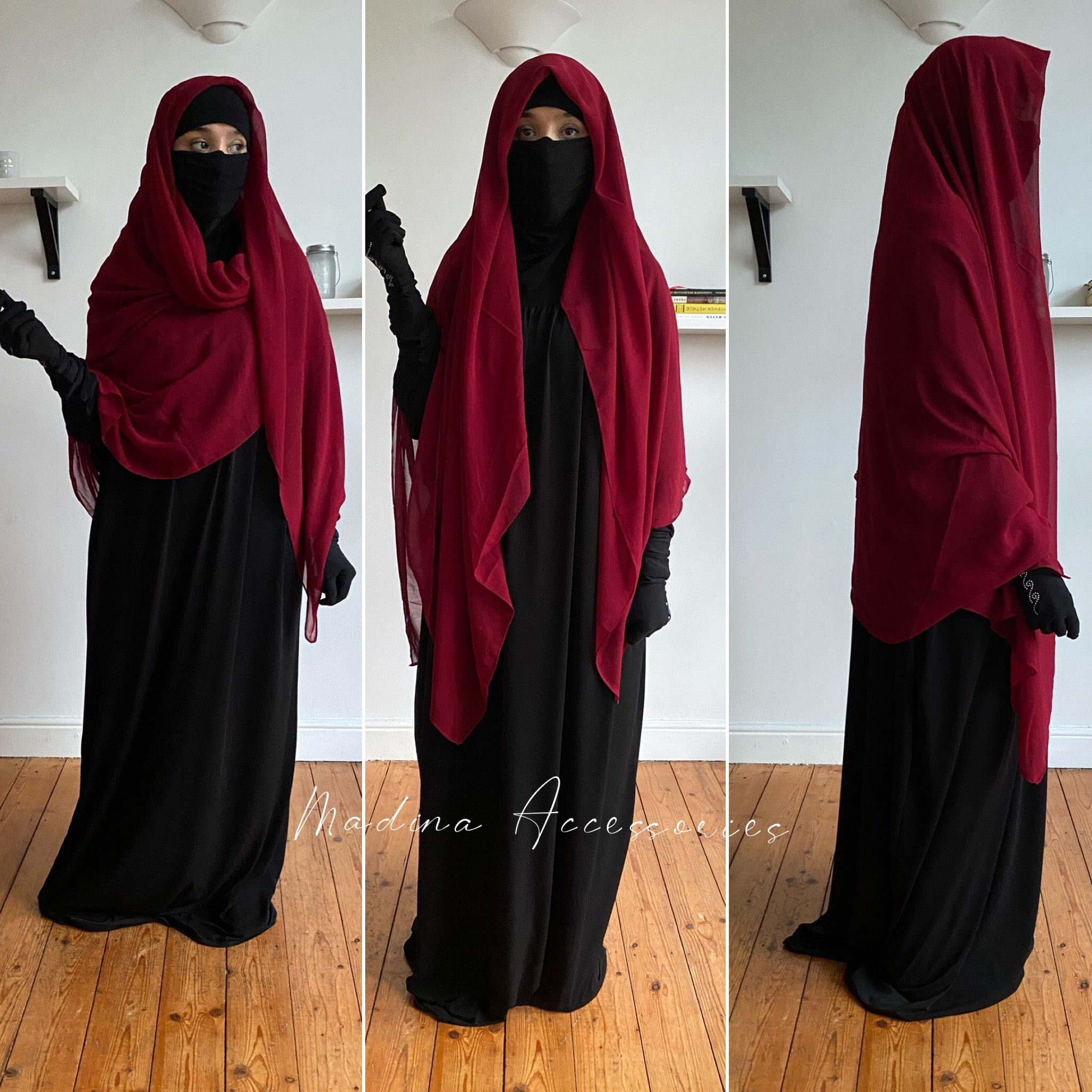 Woman in a maroon hijab draped elegantly over a black dress, posing with one hand raised, against a white interior background.